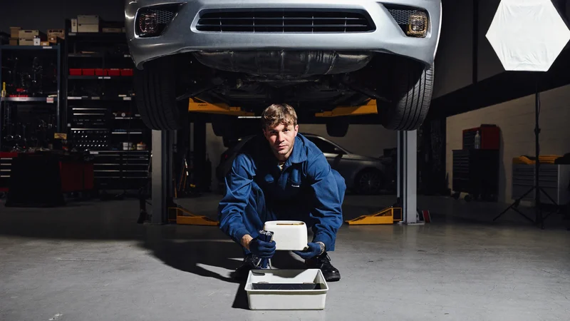 Vidange du moteur sous un véhicule levé, filtre neuf et bac de récupération propre