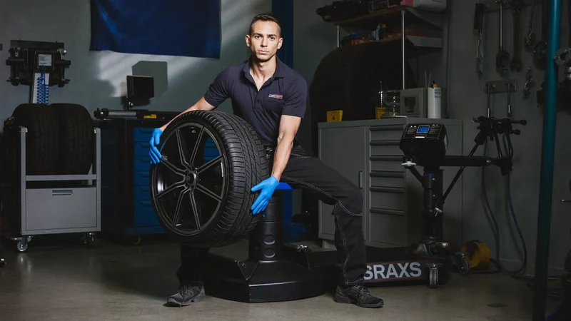 Montage d'un pneu sur jante alliage avec la machine d'équilibrage en arrière-plan